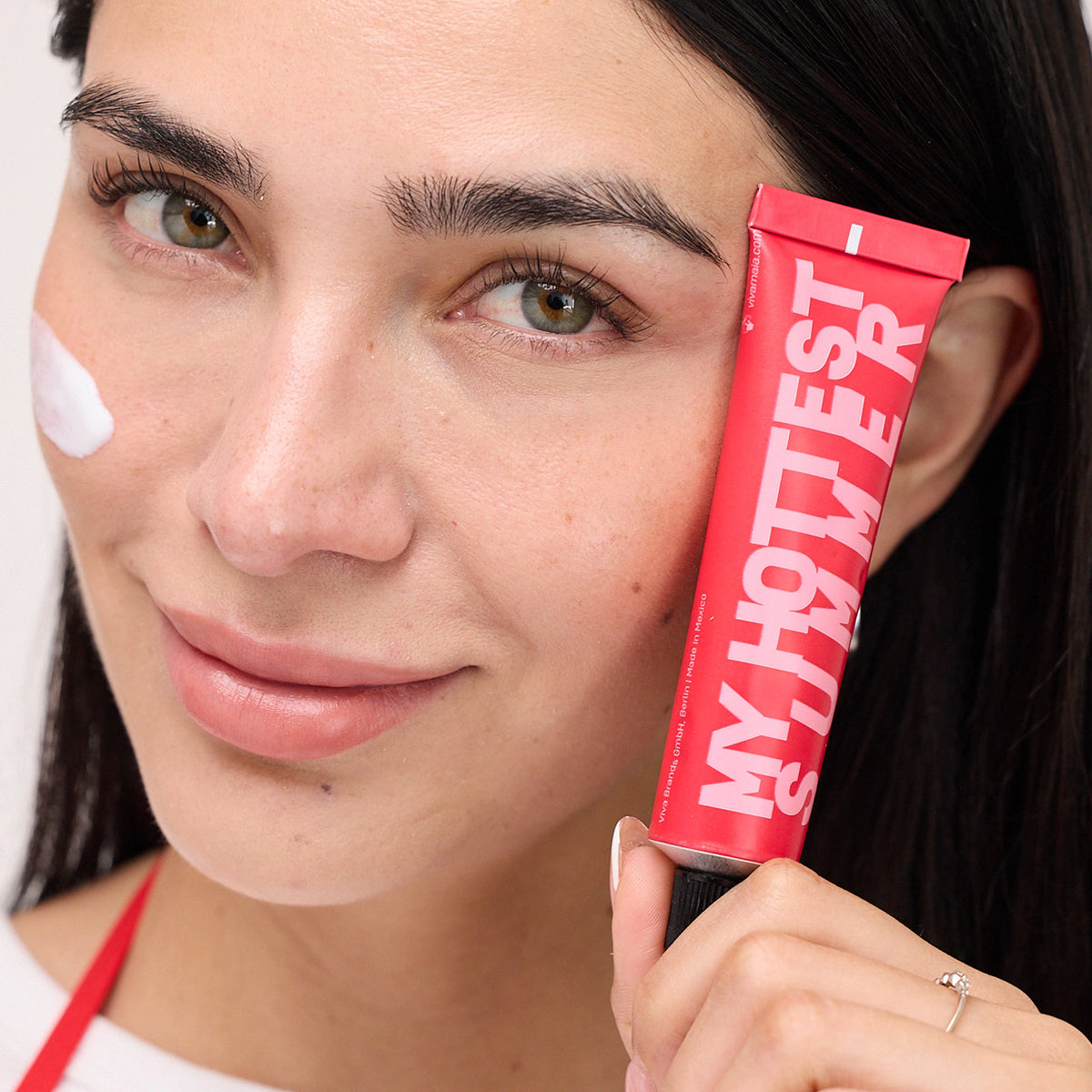 Viva Maia Tamarind & Zinc Oxide Shielding Sunscreen SPF 45+ My Hottest Summer tube held to a smiling woman's cheek.